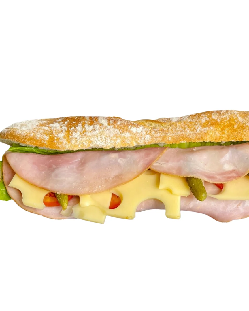 A sandwich featuring layers of ham, cheese, and pickles, all nestled in a crusty baguette with lettuce.