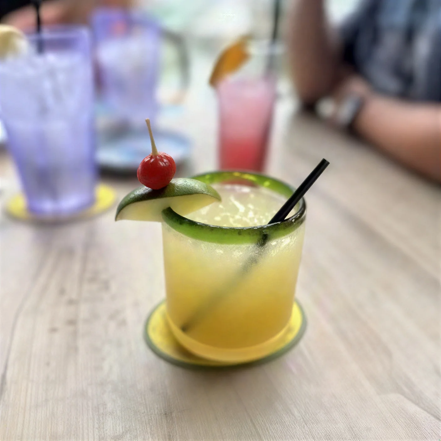 Colorful margarita cocktail with lime and cherry garnish