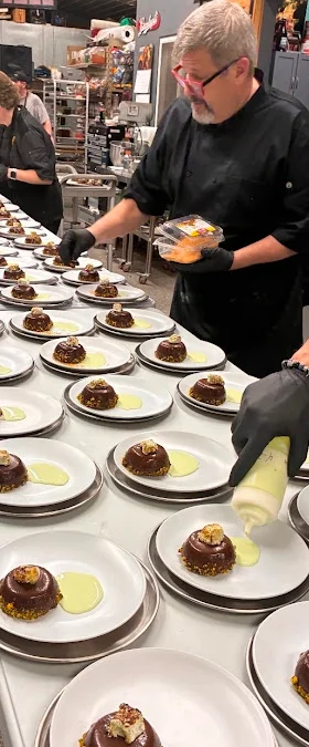 Chefs plating desserts in a busy restaurant kitchen