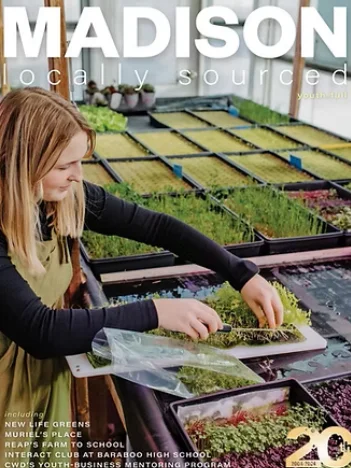 Person tending to microgreens in a greenhouse