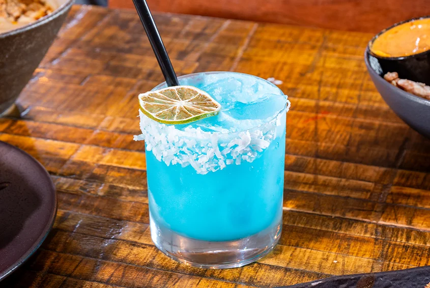 Vibrant blue cocktail with lime garnish and salt rim