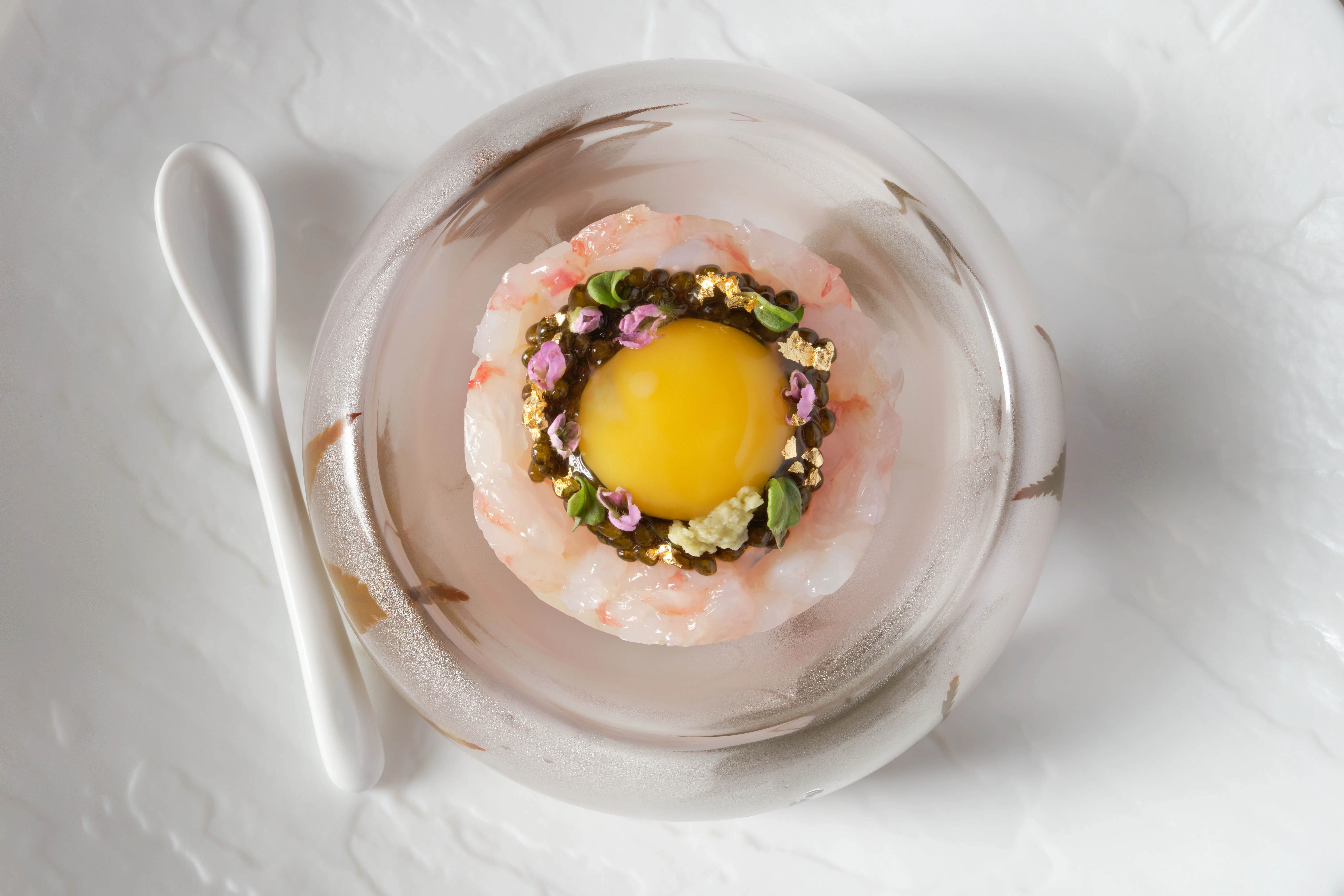 Japanese sashimi dish with egg yolk and garnishes in a glass bowl