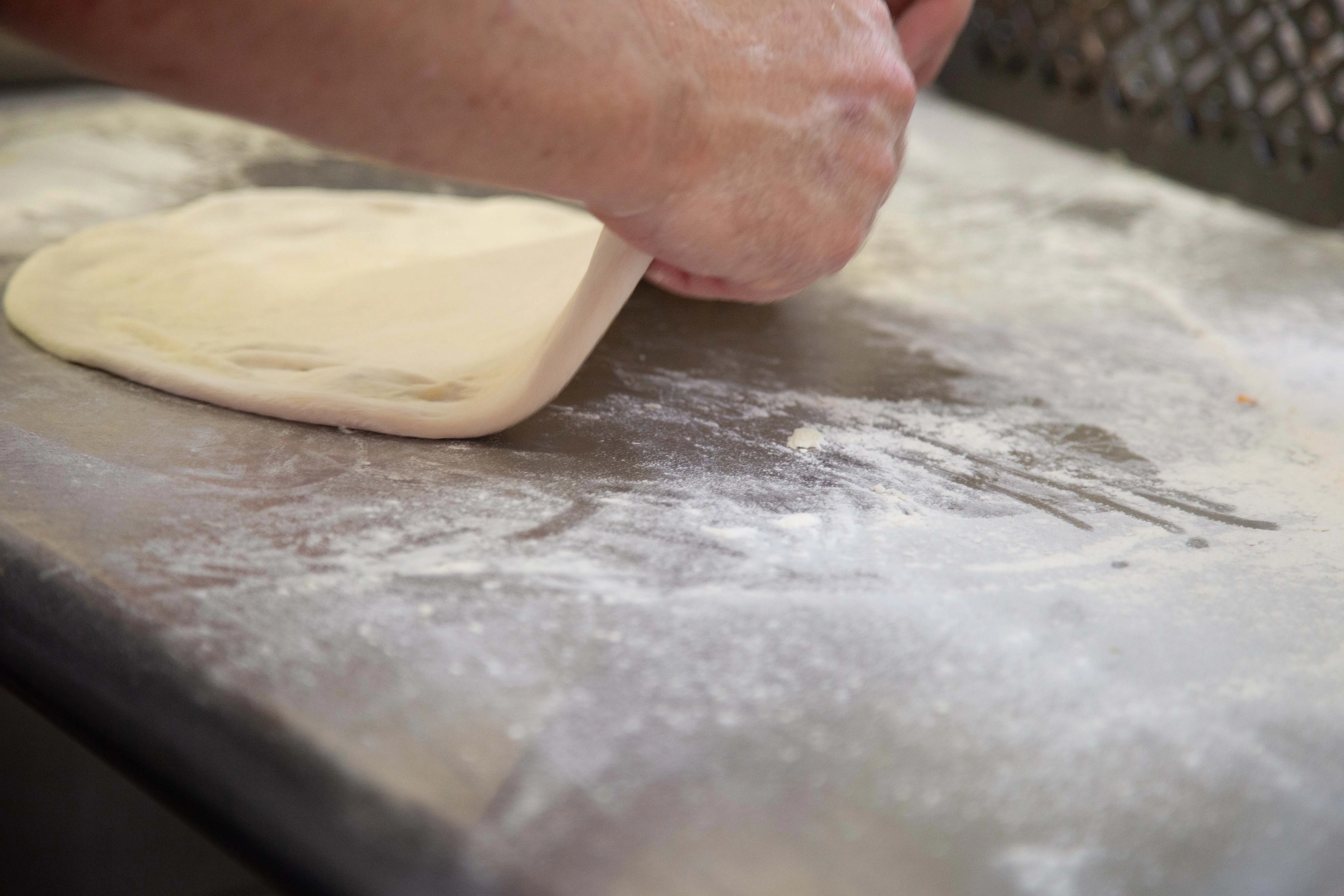Chef stretching pizza dough on a floured surface