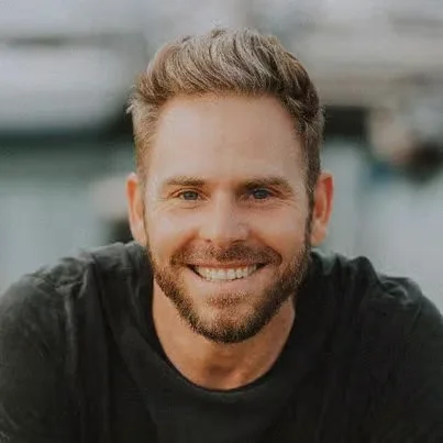 Smiling man with beard in casual attire outdoors