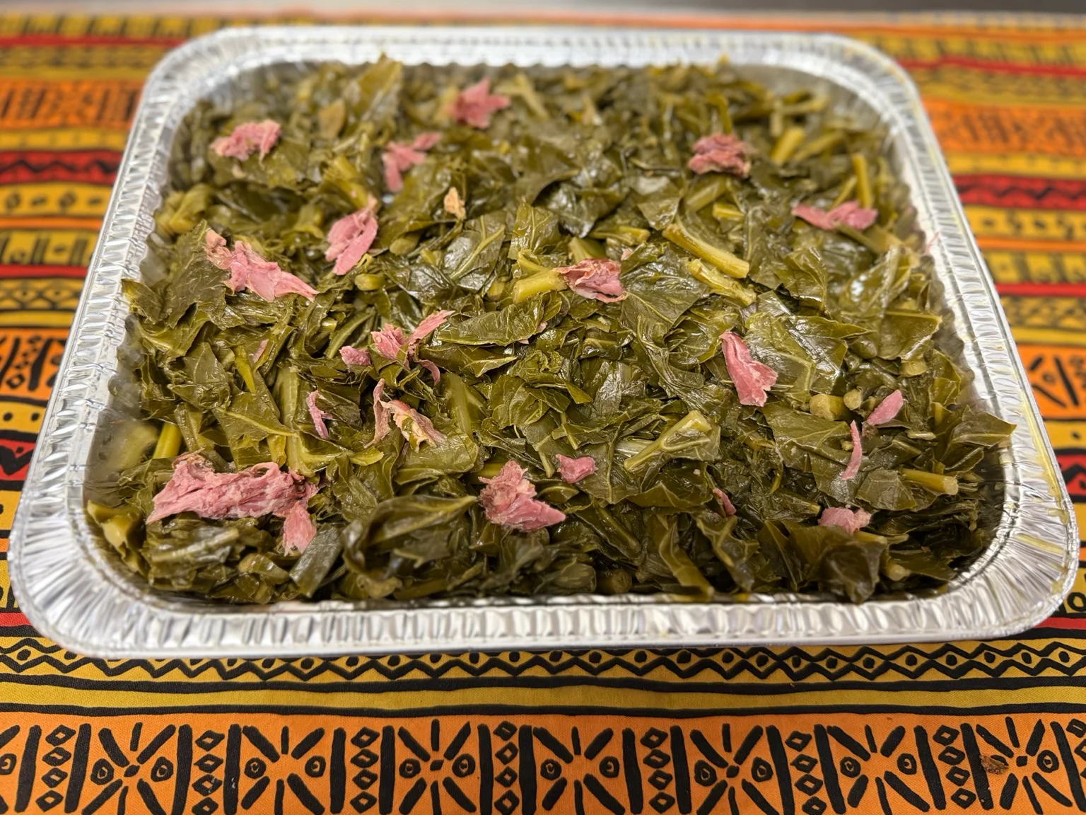 A plate featuring a variety of Southern dishes including mac and cheese, rice, collard greens, and sweet potato. Each item is served in its own bowl.