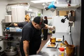 Chef plating a gourmet dish in a busy restaurant kitchen