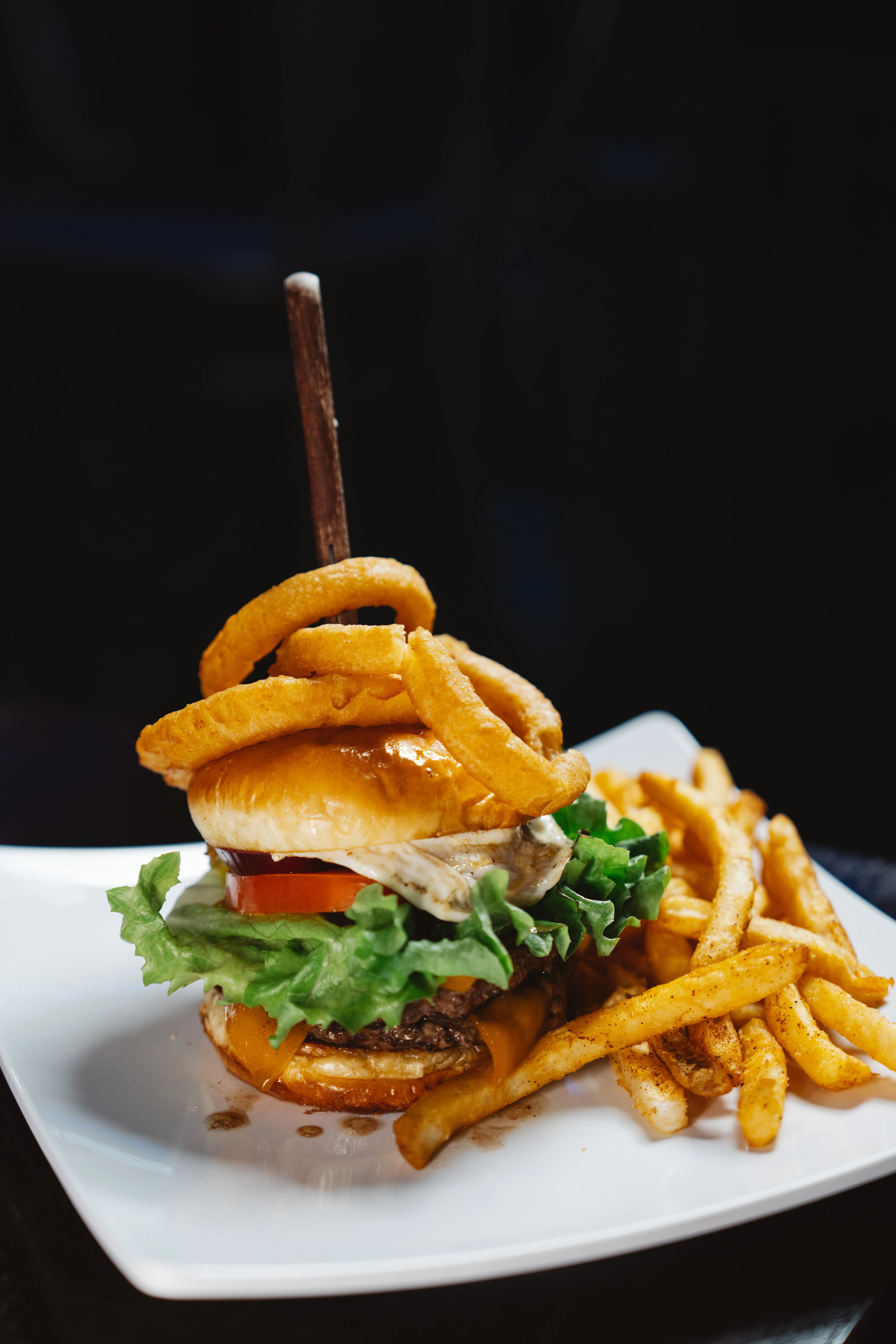 Juicy American cheeseburger with onion rings and fries