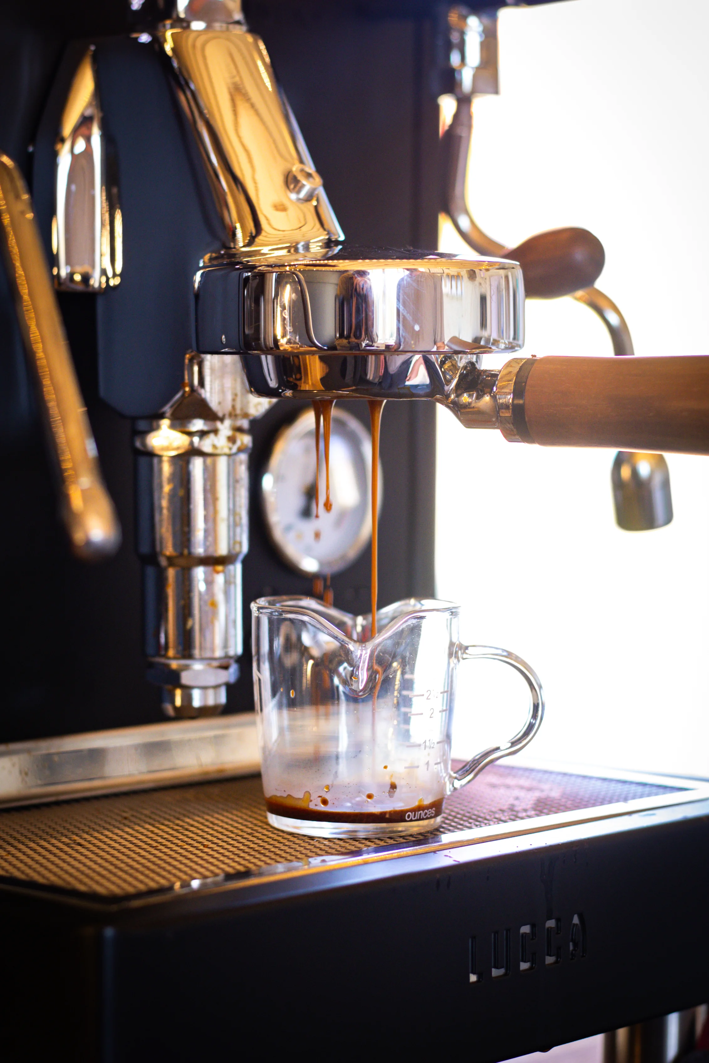 Espresso pouring from a coffee machine into a glass jug