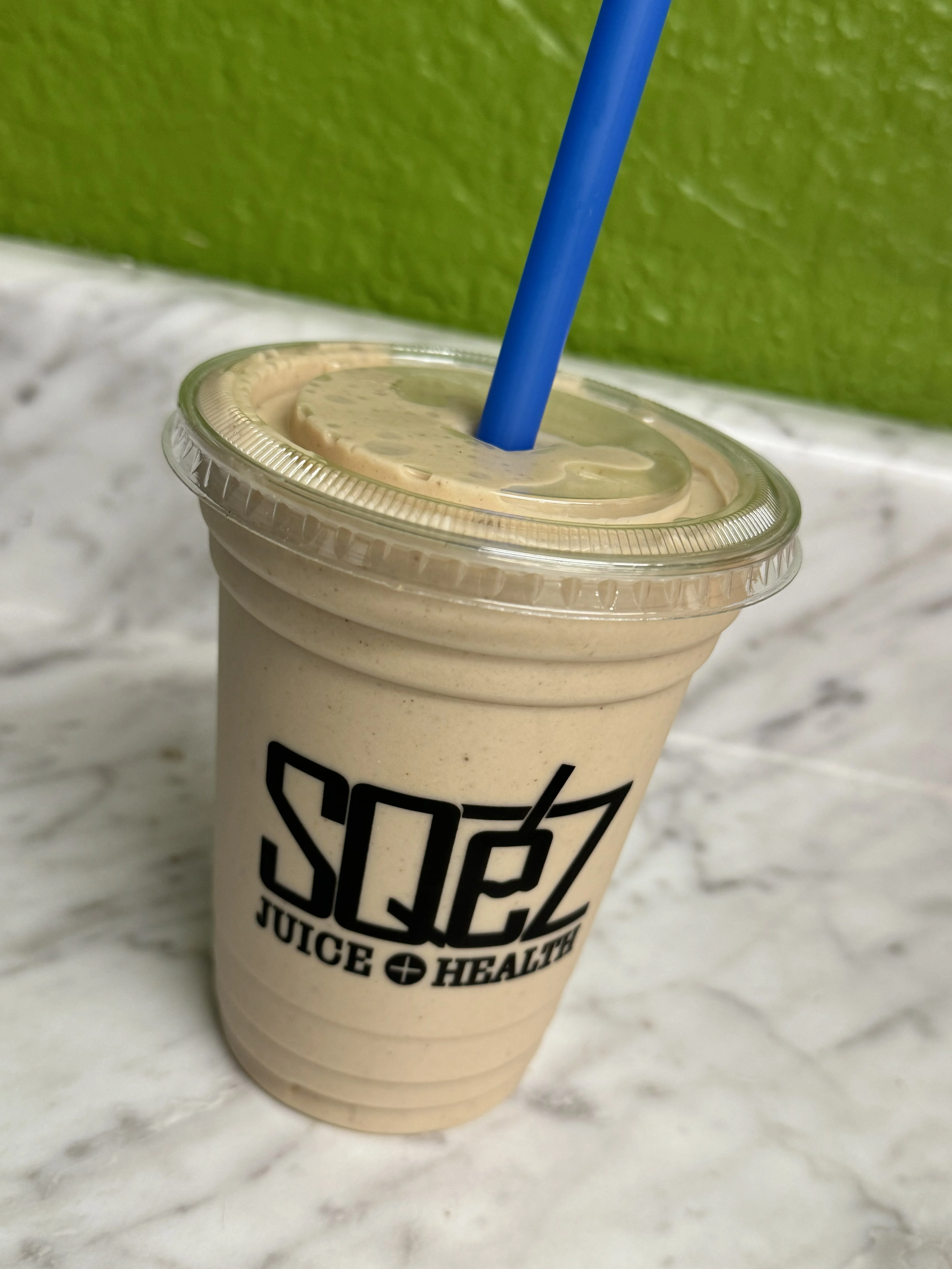A vibrant smoothie with fruits and greens in a clear glass.
