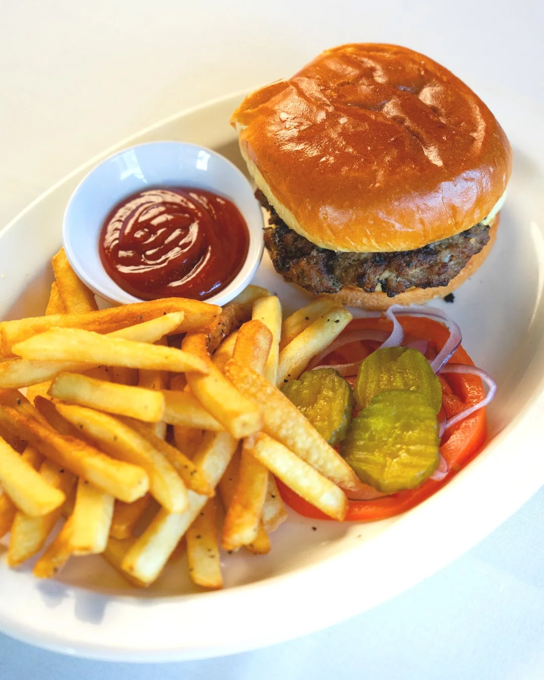 A classic cheeseburger served with fries, pickles, and ketchup on the side.