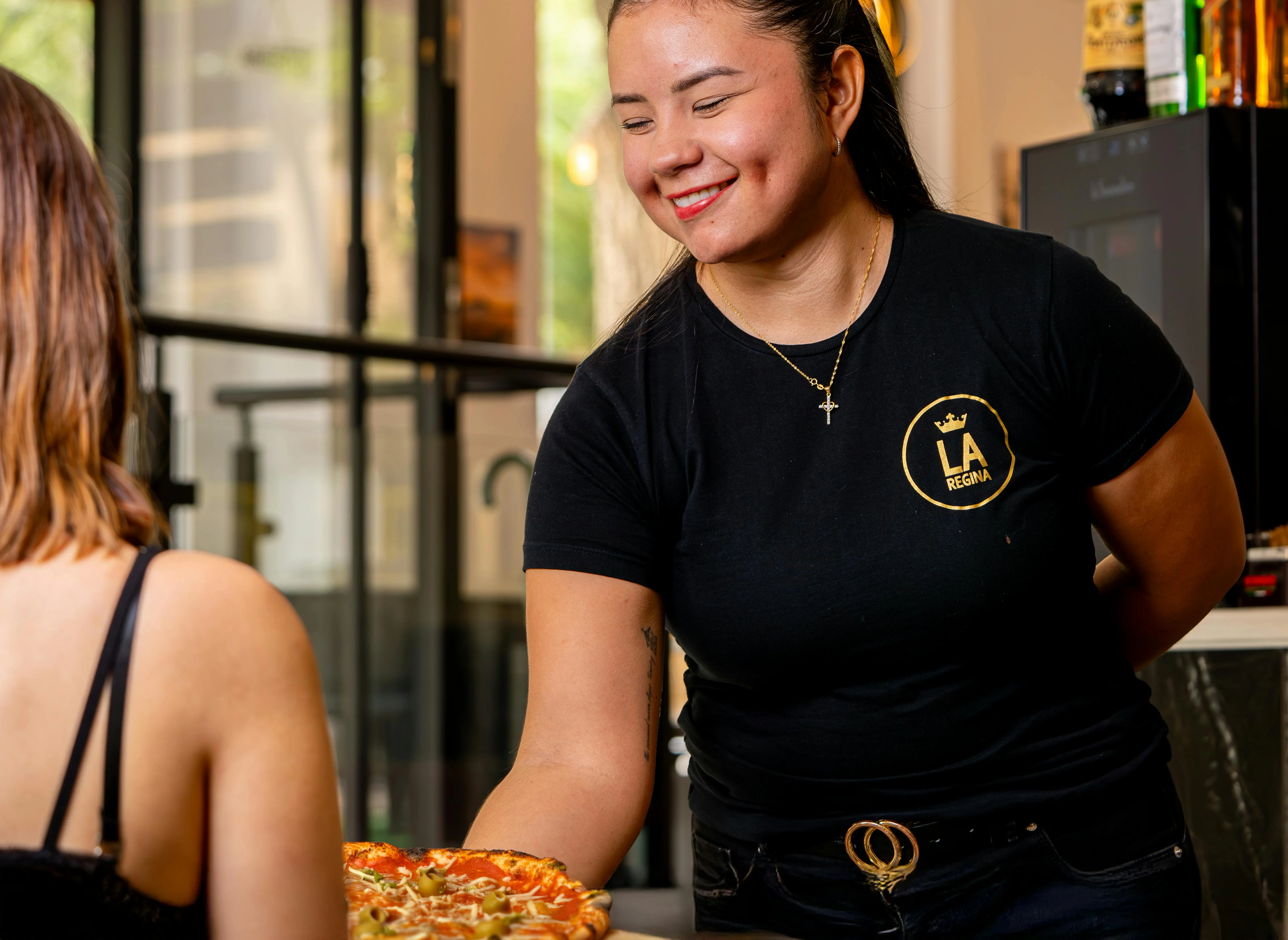 Friendly server presenting a delicious pizza in a cozy restaurant setting