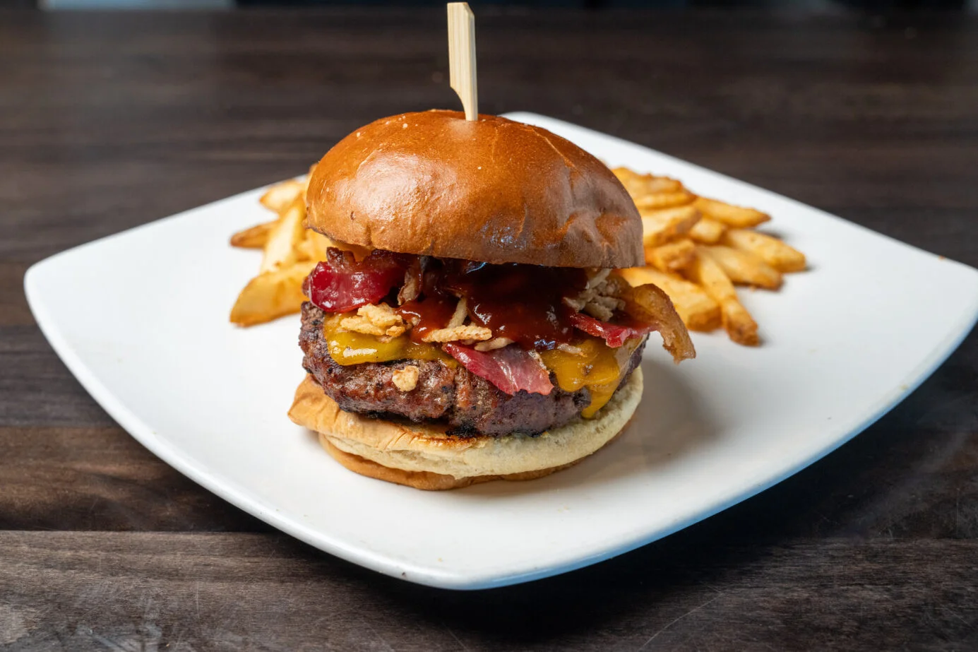 Juicy American cheeseburger with fries on a white plate