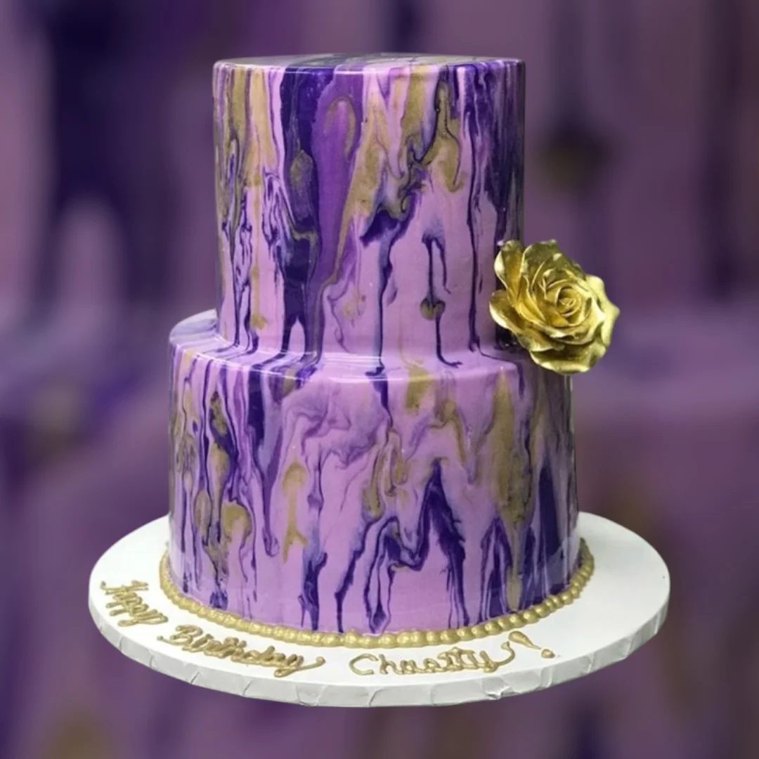 Elegant two-tiered birthday cake with purple marbling and gold accents