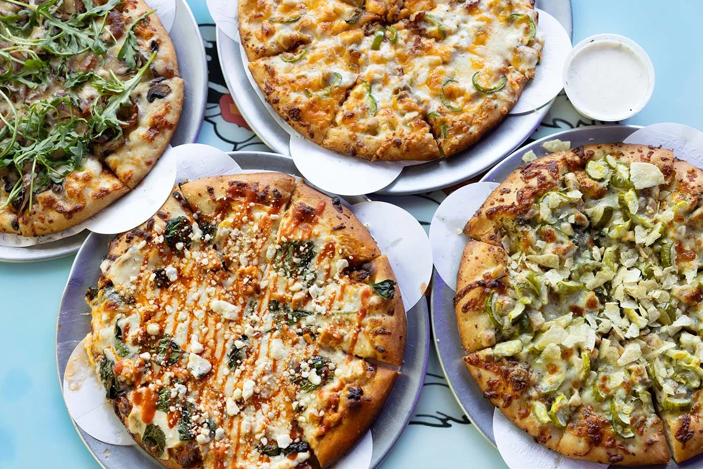 Variety of gourmet pizzas on metal trays in a vibrant setting