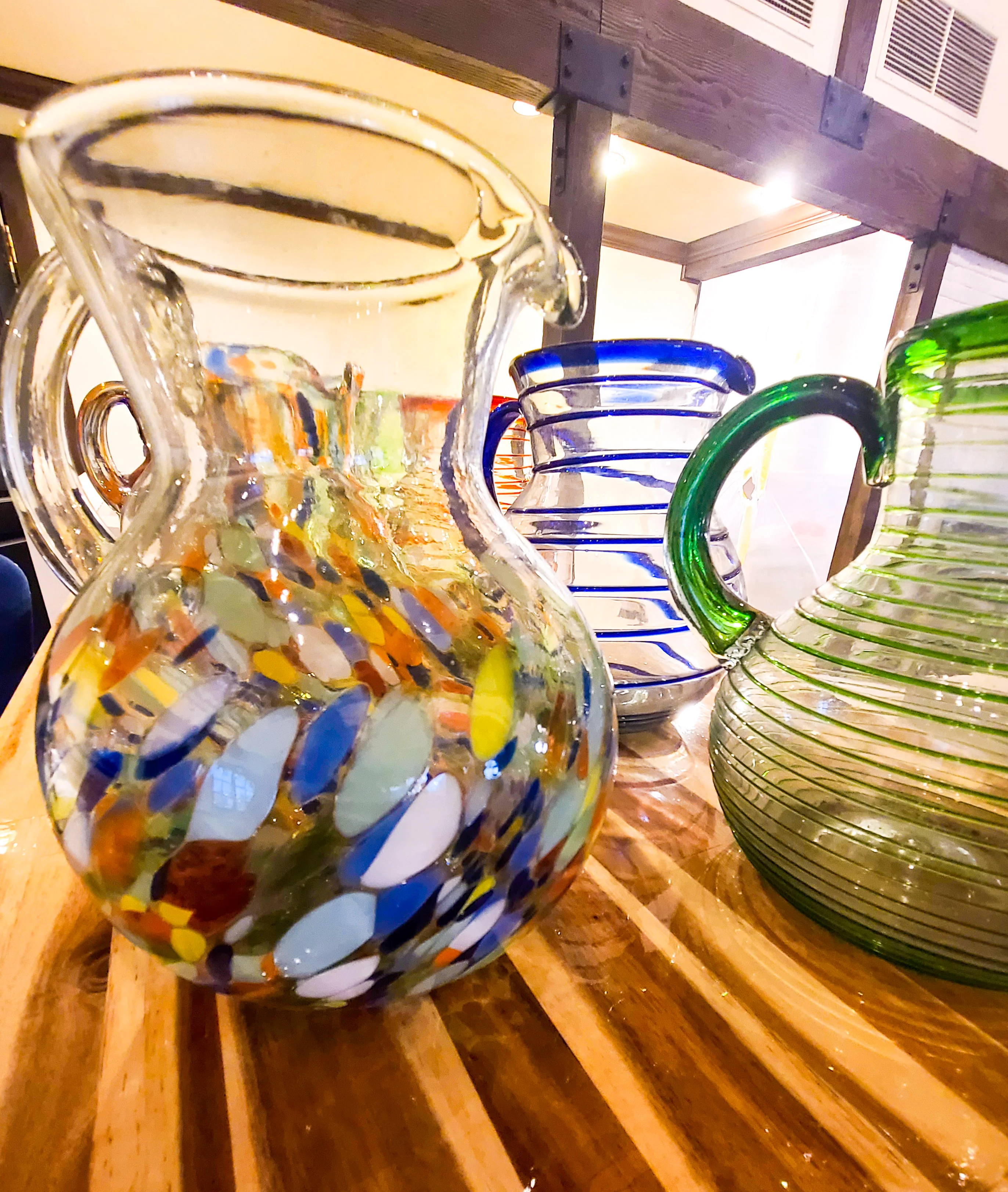 Colorful glass pitchers displayed on a wooden table