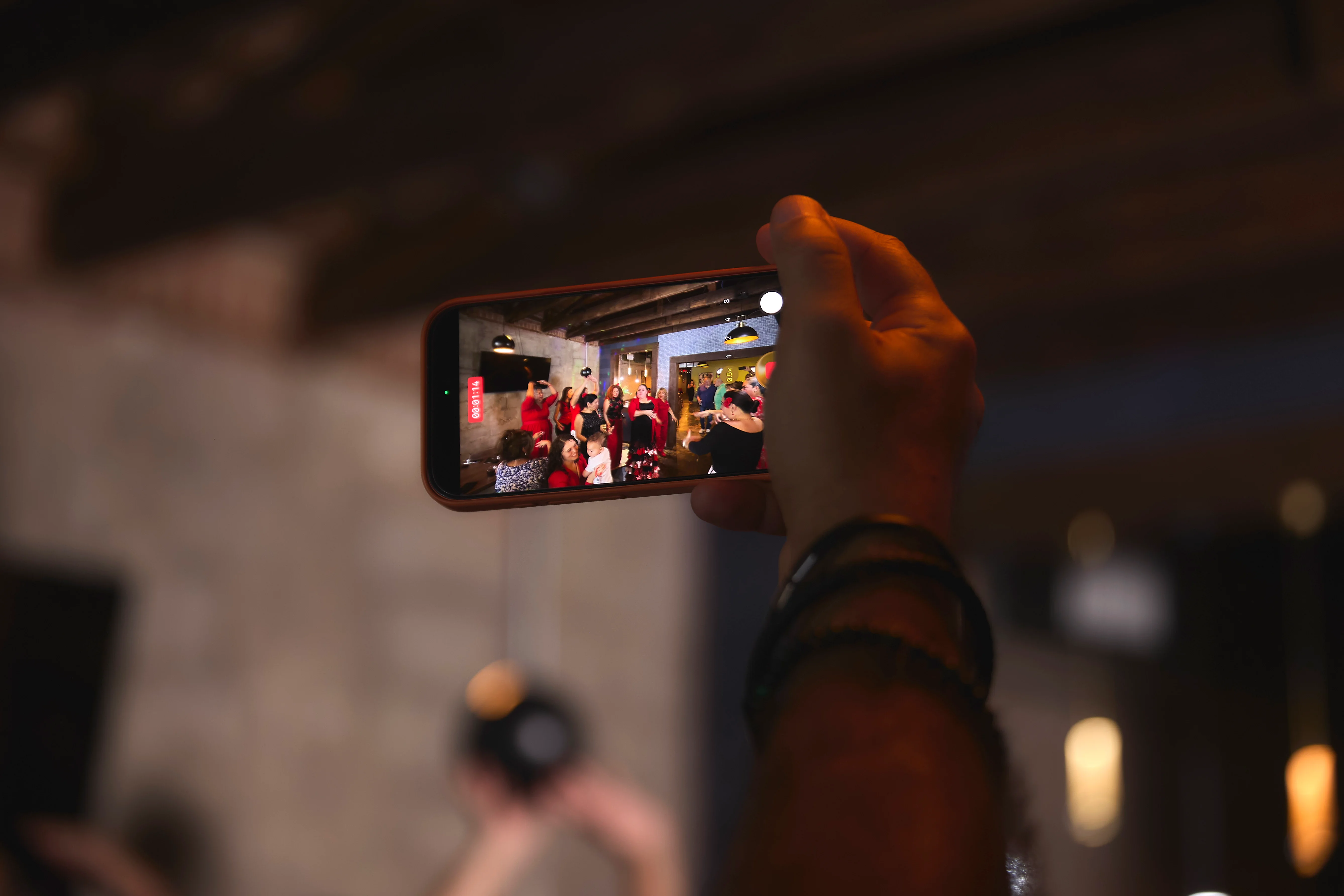 Person filming a lively restaurant event with a smartphone