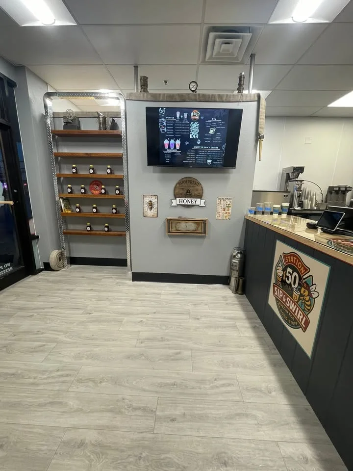 An interior view of a beverage shop featuring a menu display, honey jars on shelves, and a cozy atmosphere.