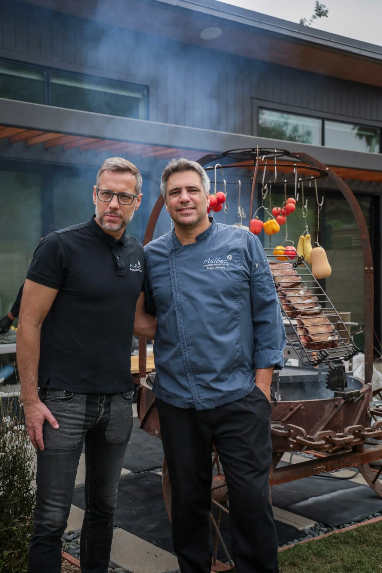 Chefs grilling Argentine asado outdoors with colorful vegetables