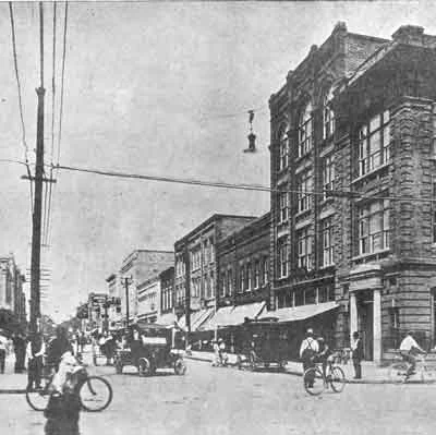 Historic street scene with vintage cars and bicycles
