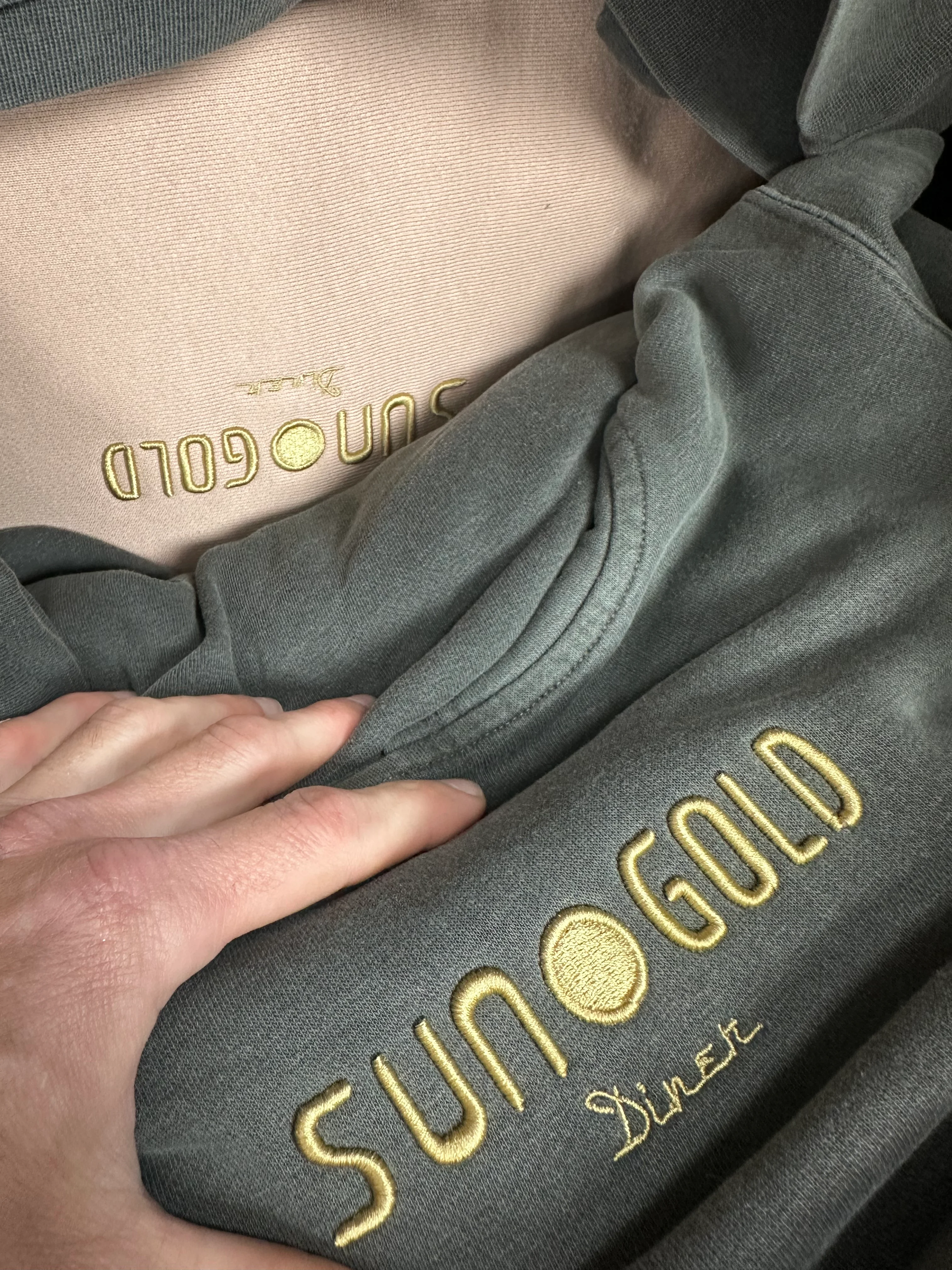 A collection of clothing items with 'Sun Gold Diner' embroidered, showcasing different colors and textures.