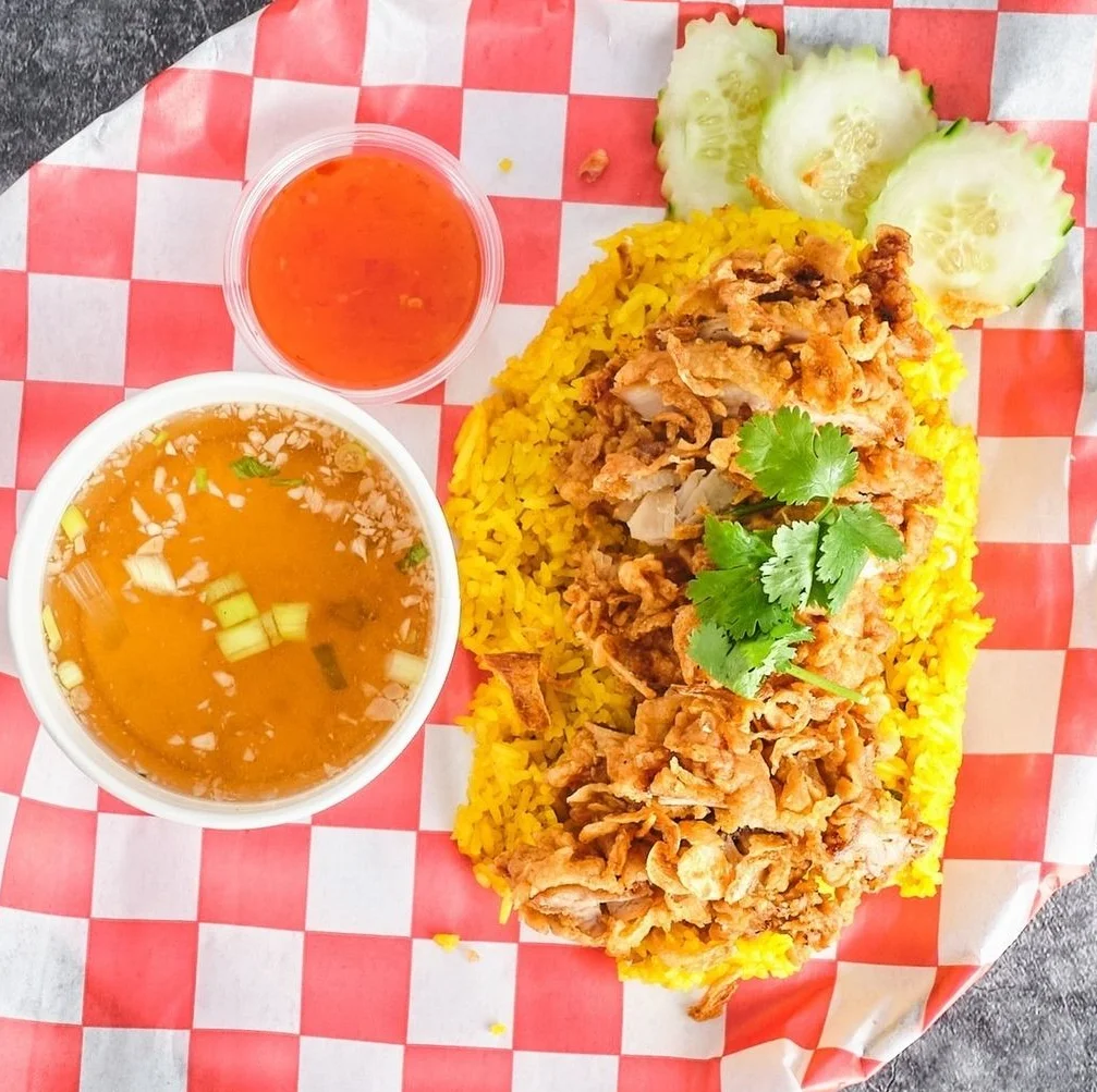 Golden yellow chicken biryani served with soup and chili sauce
