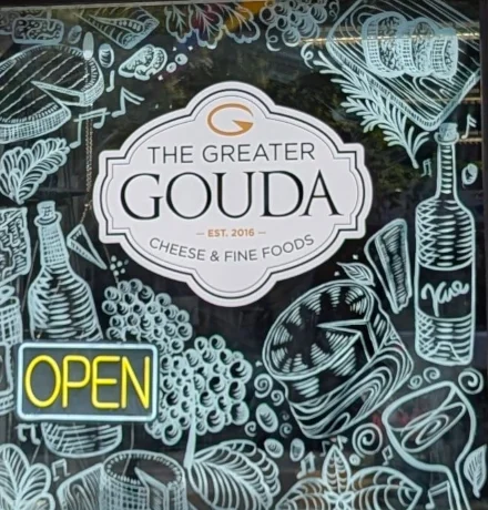A window with cheese, grapes, wine, and other foodstuffs drawn in white paint