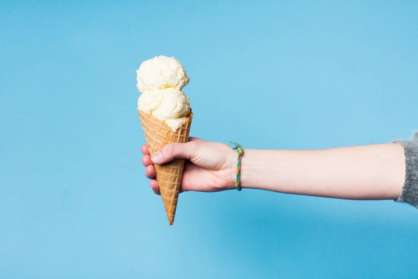 Classic vanilla ice cream cone held against a blue background
