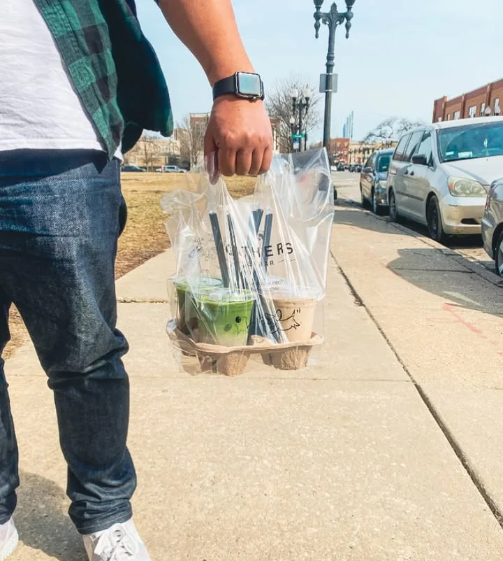 Takeout drinks in a carrier on a sunny sidewalk