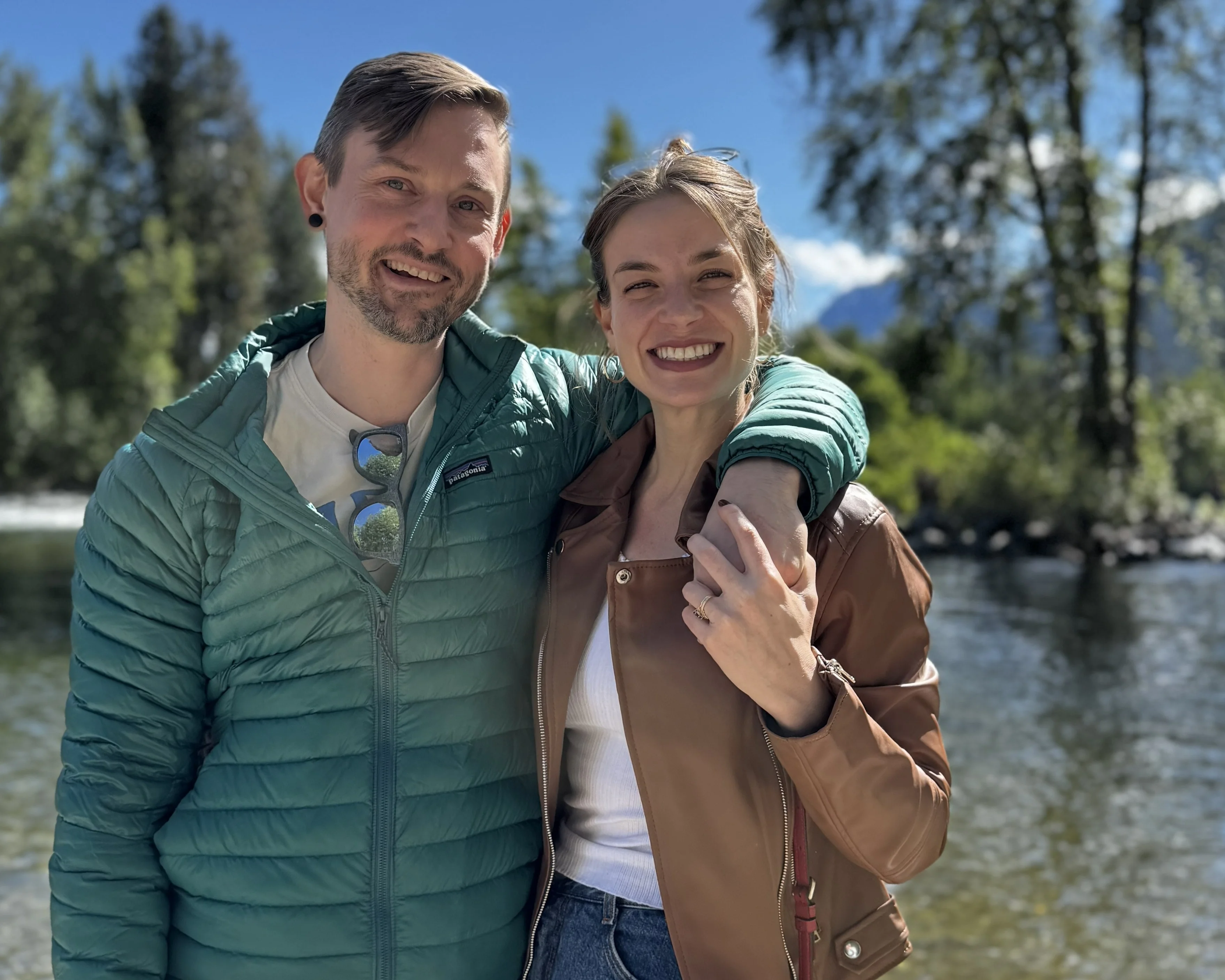 Couple smiling by a river in a scenic outdoor setting