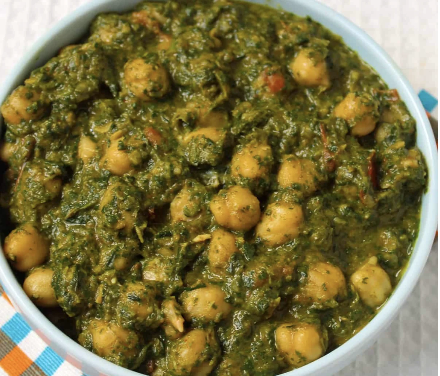 A bowl of spinach and chickpeas mixed together, showcasing a vibrant green color with hints of spices.