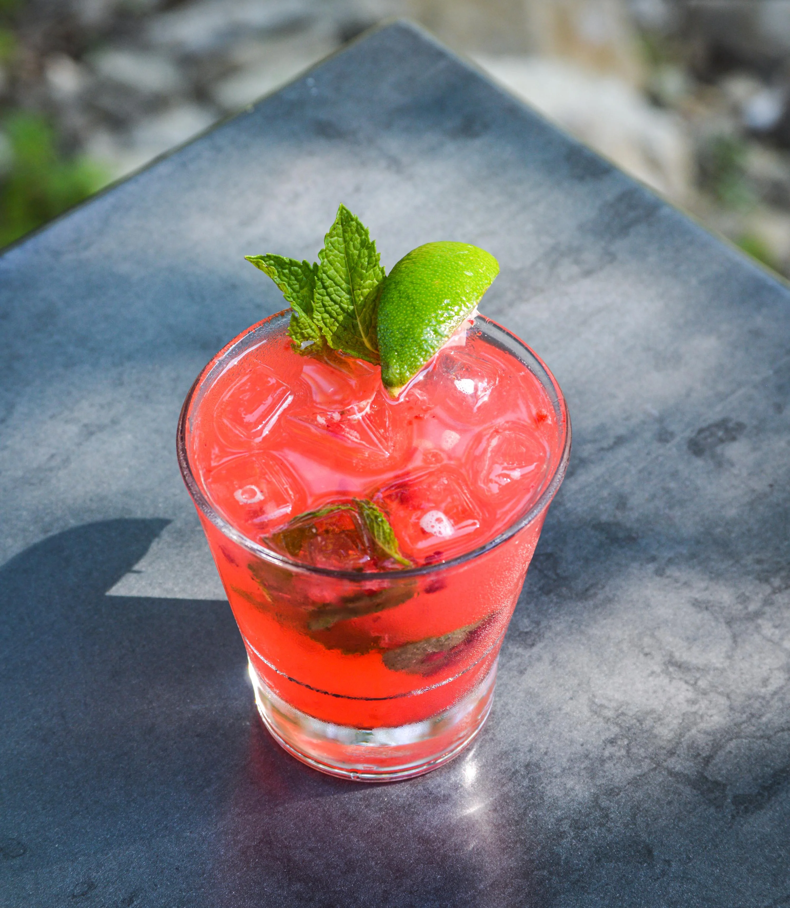 Raspberry Mojito on a sunny patio table with mint sprigs on the top