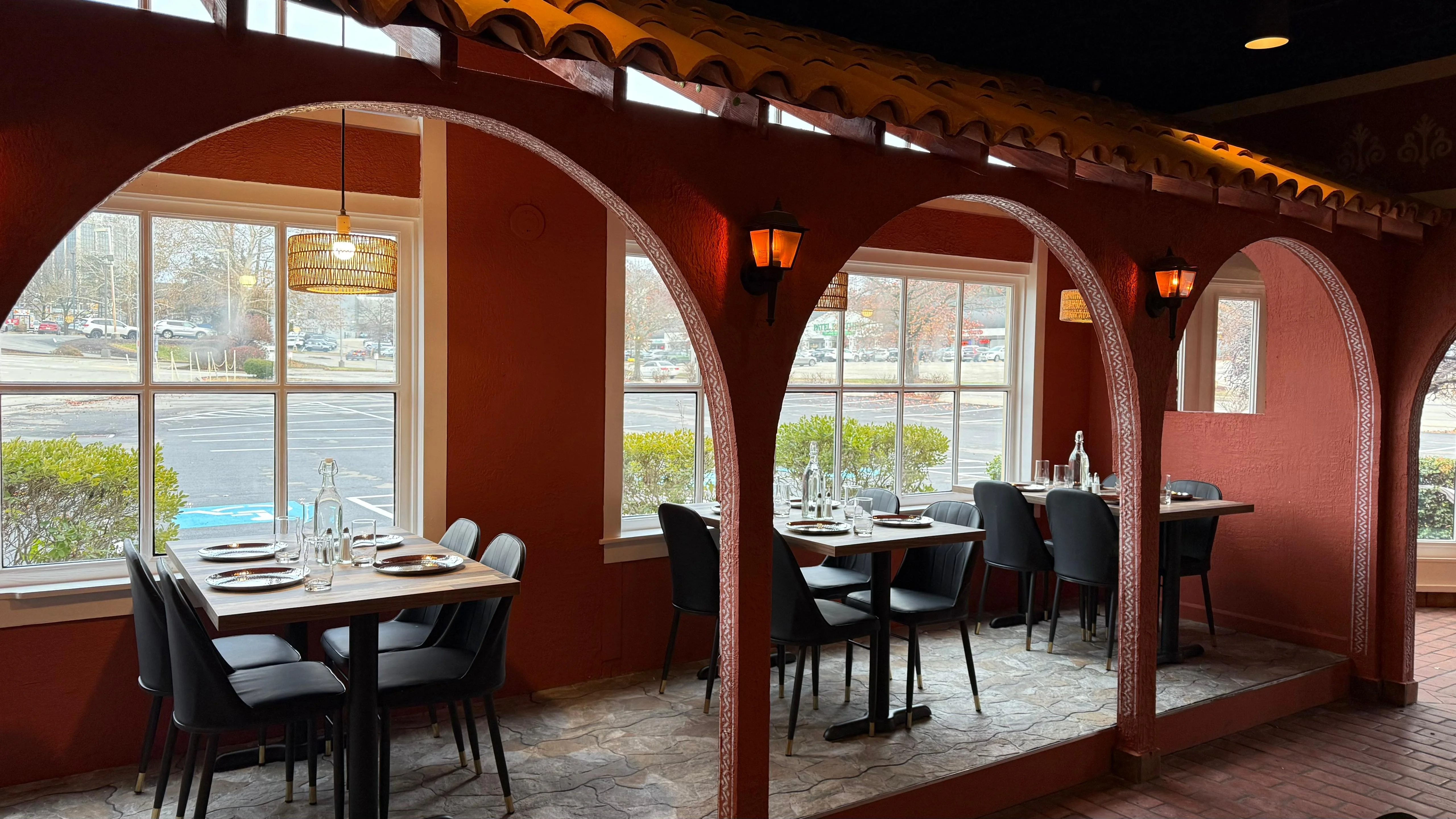 A cozy dining space featuring arched windows and tables set for dining. The warm tones and decor create an inviting atmosphere.