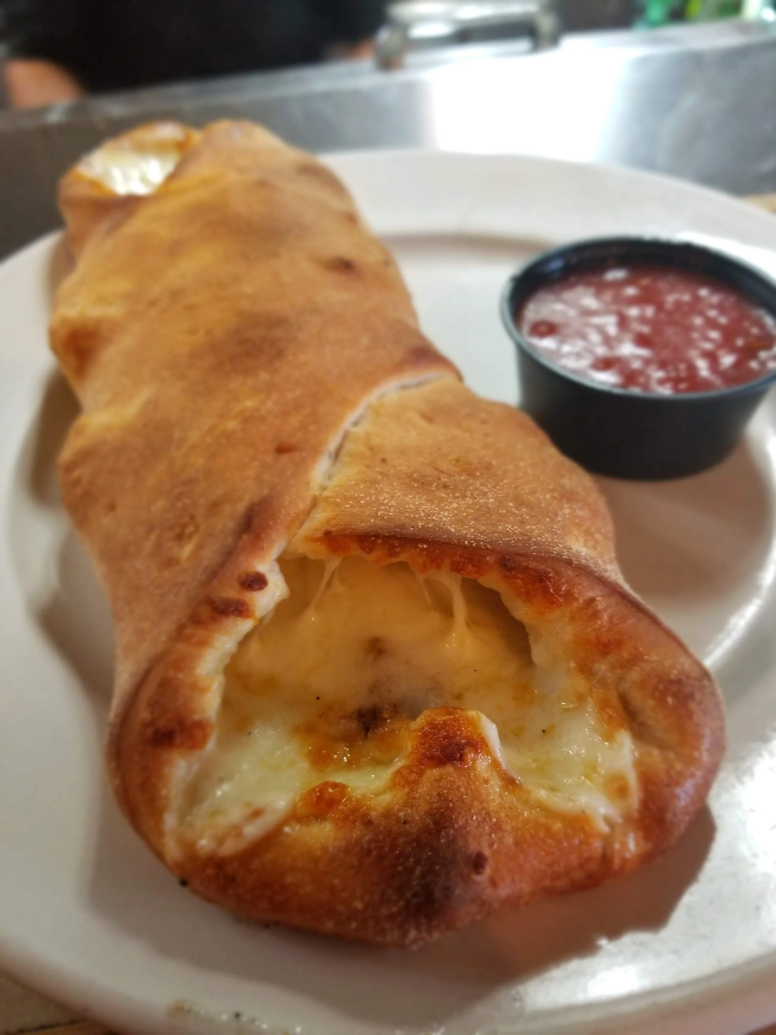 Cheesy calzone served with marinara sauce