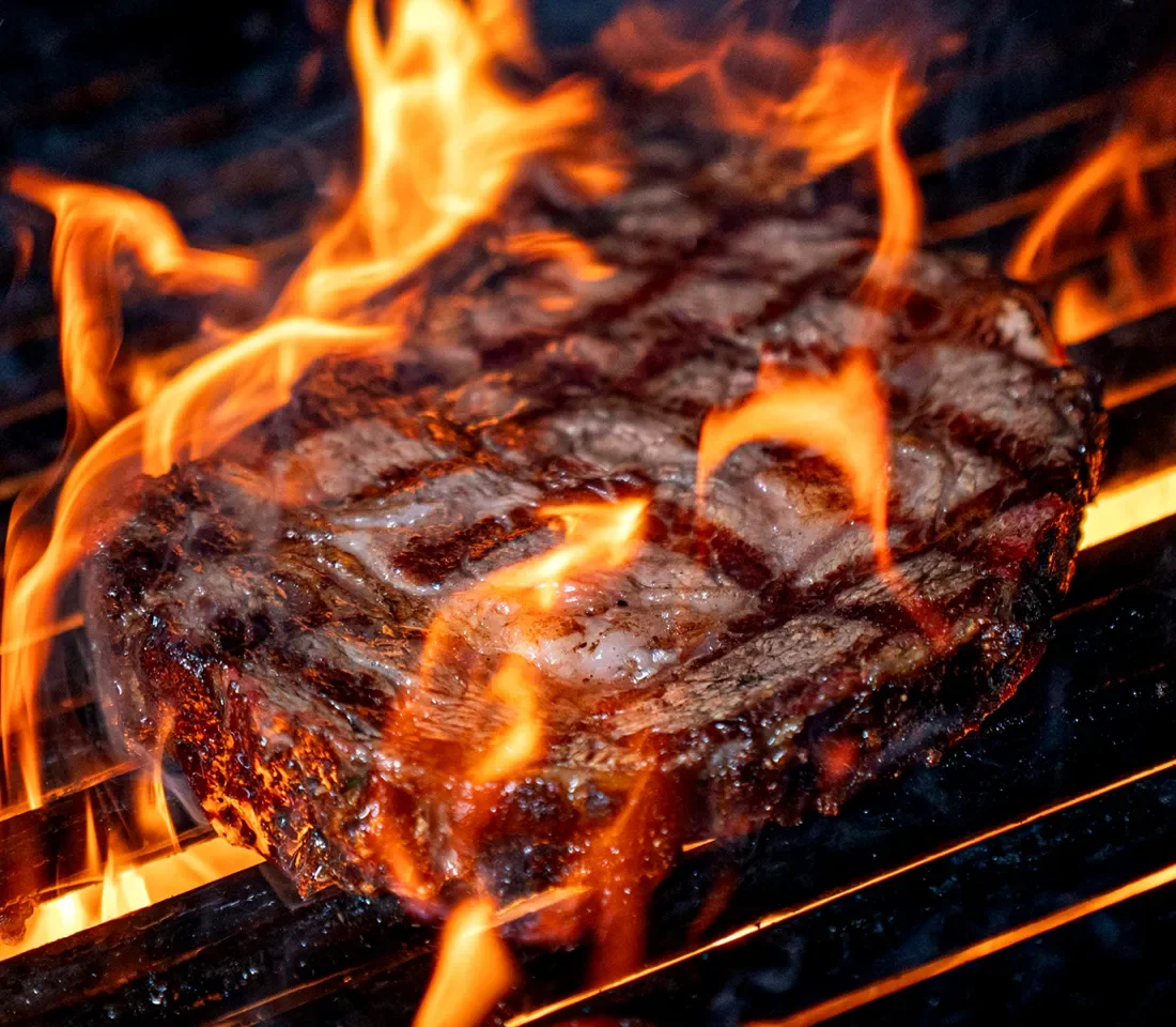 Grilled steak sizzling over an open flame