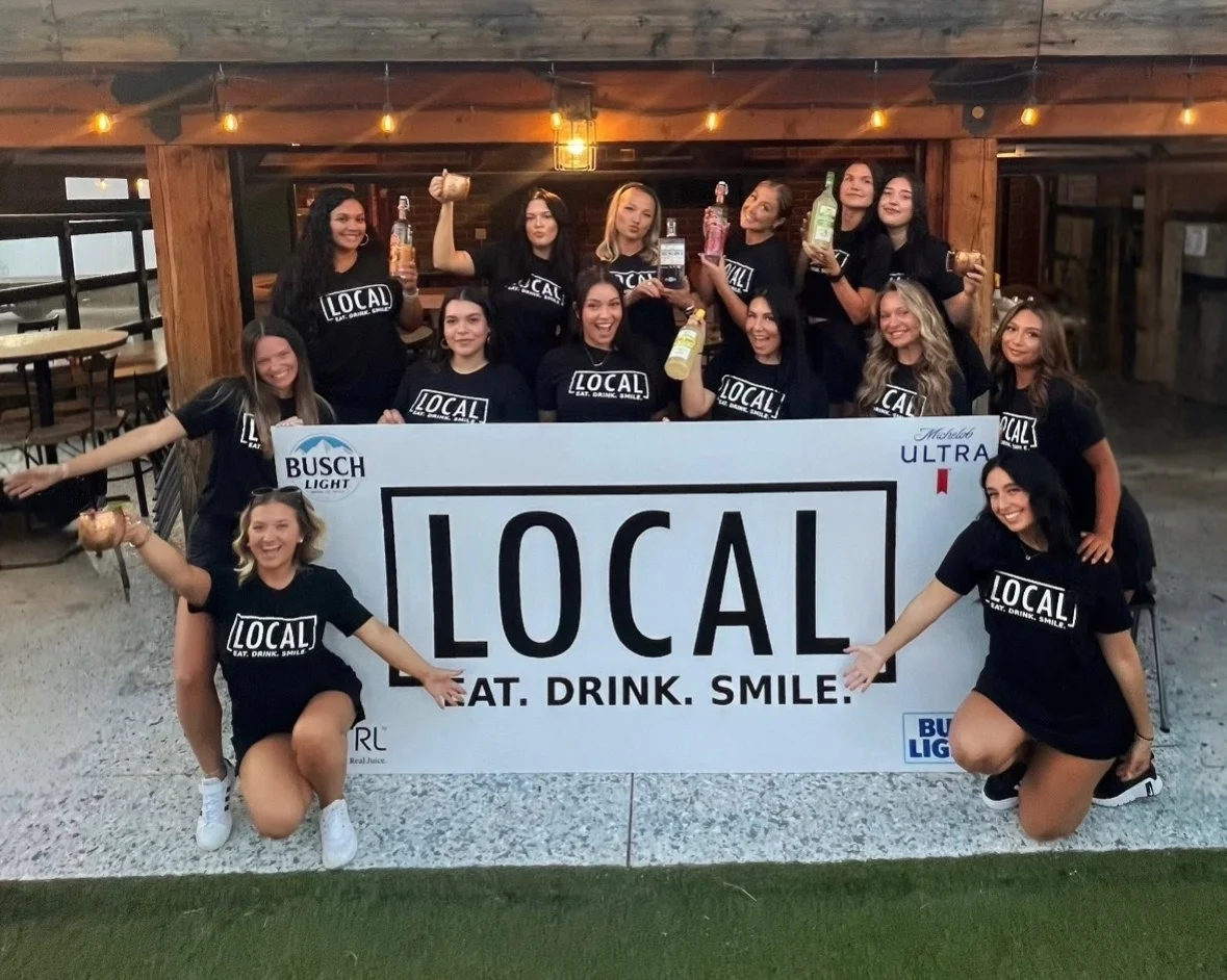 Group of staff celebrating at a local restaurant with drinks and a sign