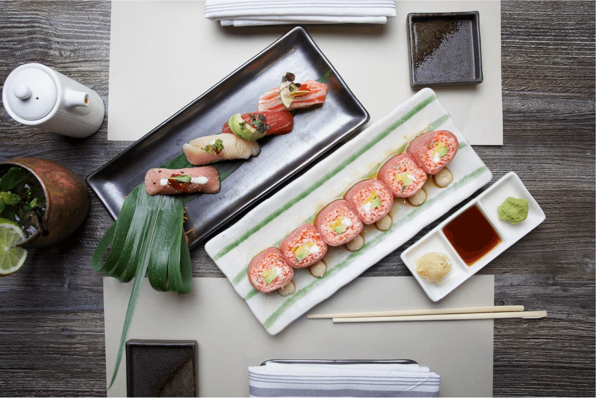A variety of sushi rolls and nigiri platters served with a bottled Japanese craft beer on a restaurant table.