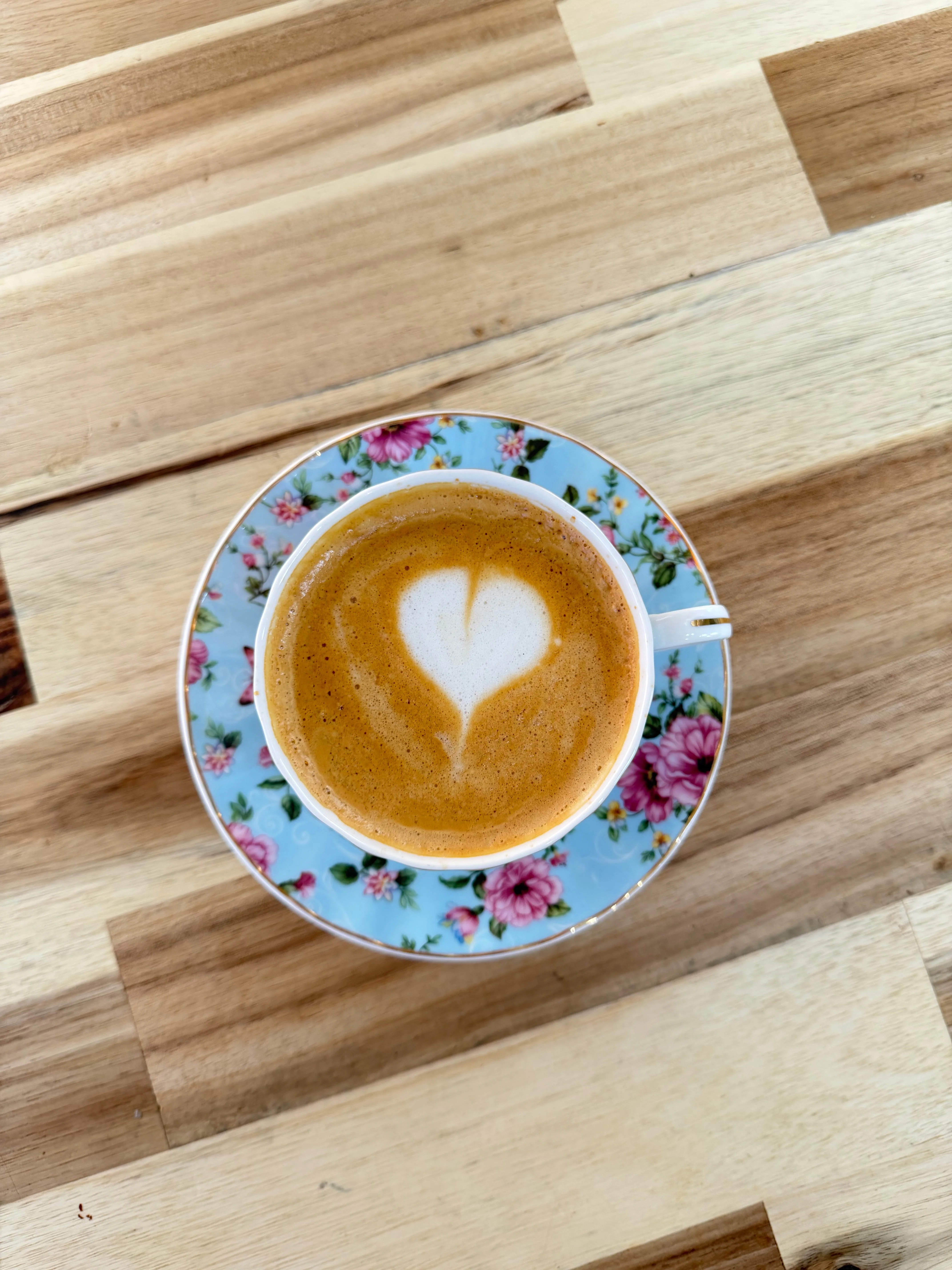 Artisan cappuccino with heart latte art on floral saucer