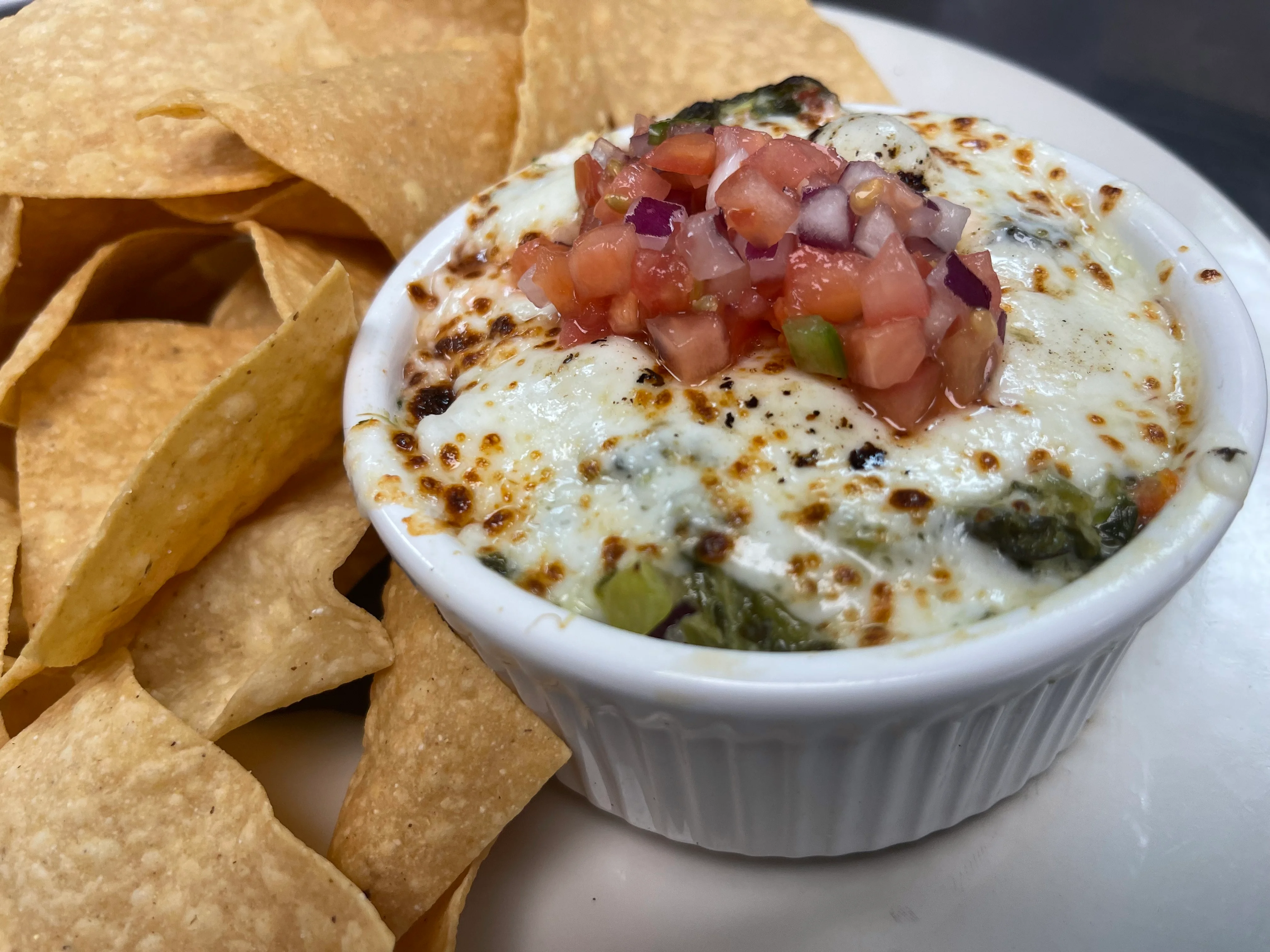 Middle Eastern hummus platter topped with tomato and onion, served with pita chips