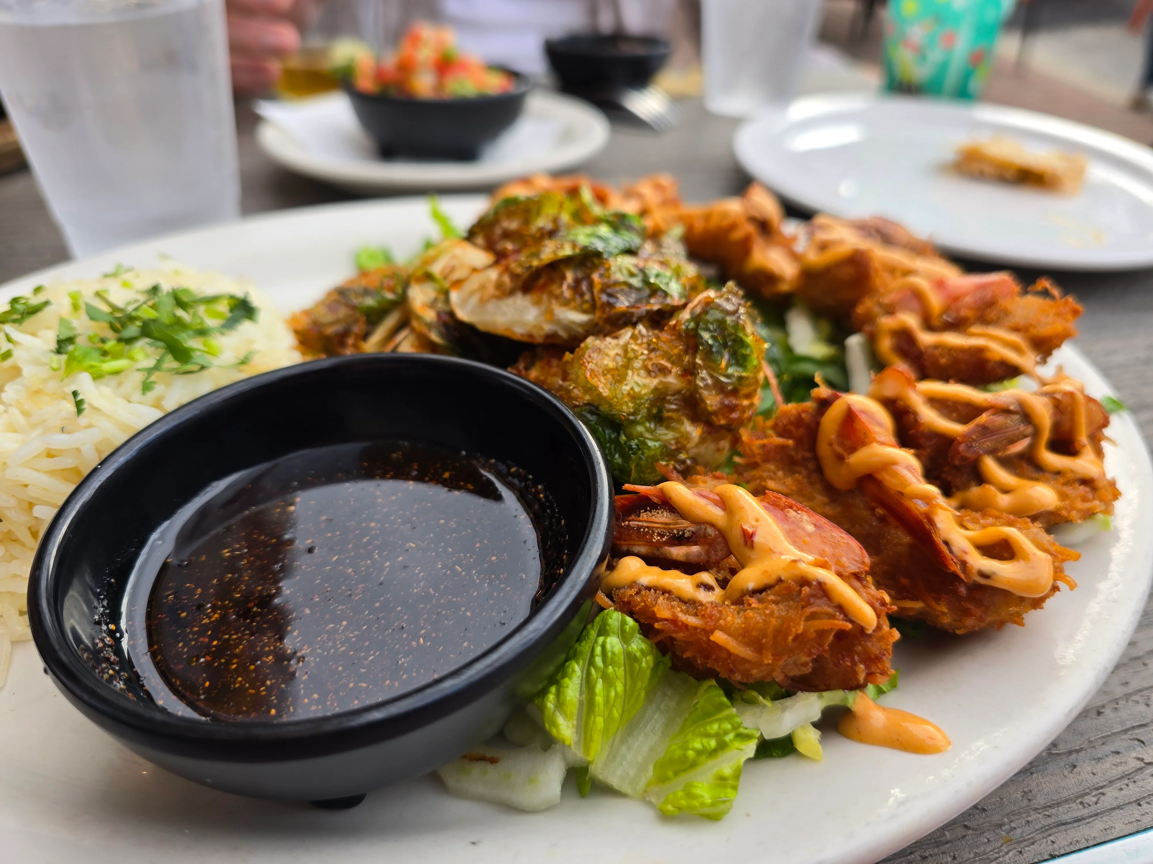 Plate of fried shrimp, rice, and dipping sauce with greens.
