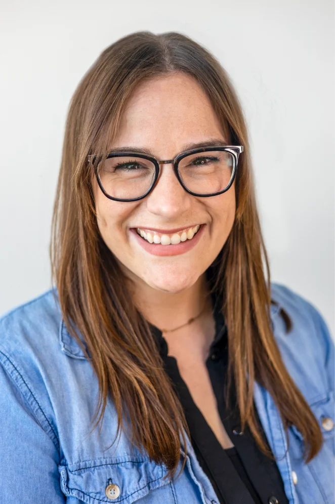 Smiling woman with glasses in a casual denim shirt