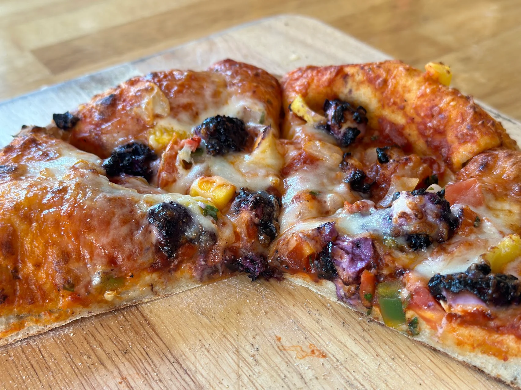 Vegetarian pizza with colorful toppings on a wooden board