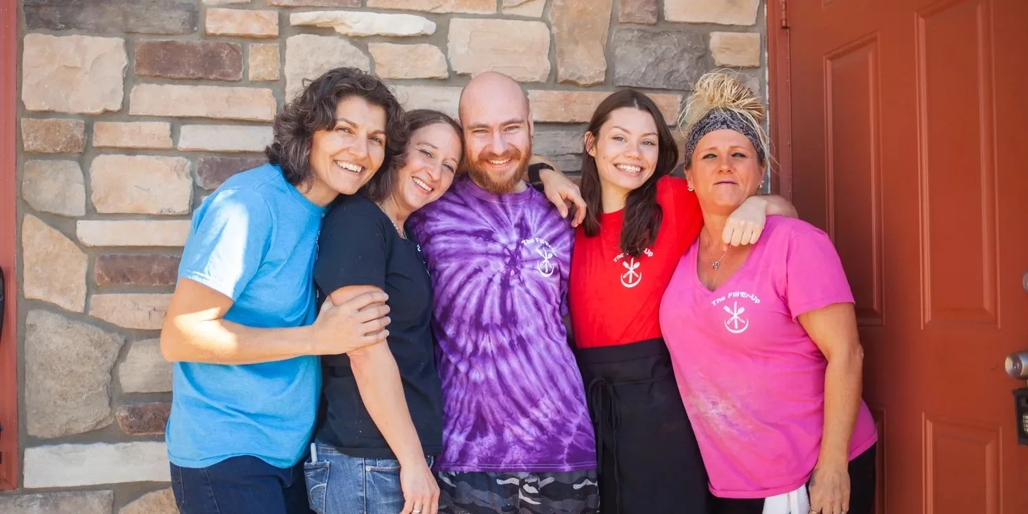 Friendly restaurant staff posing together outside a cozy eatery