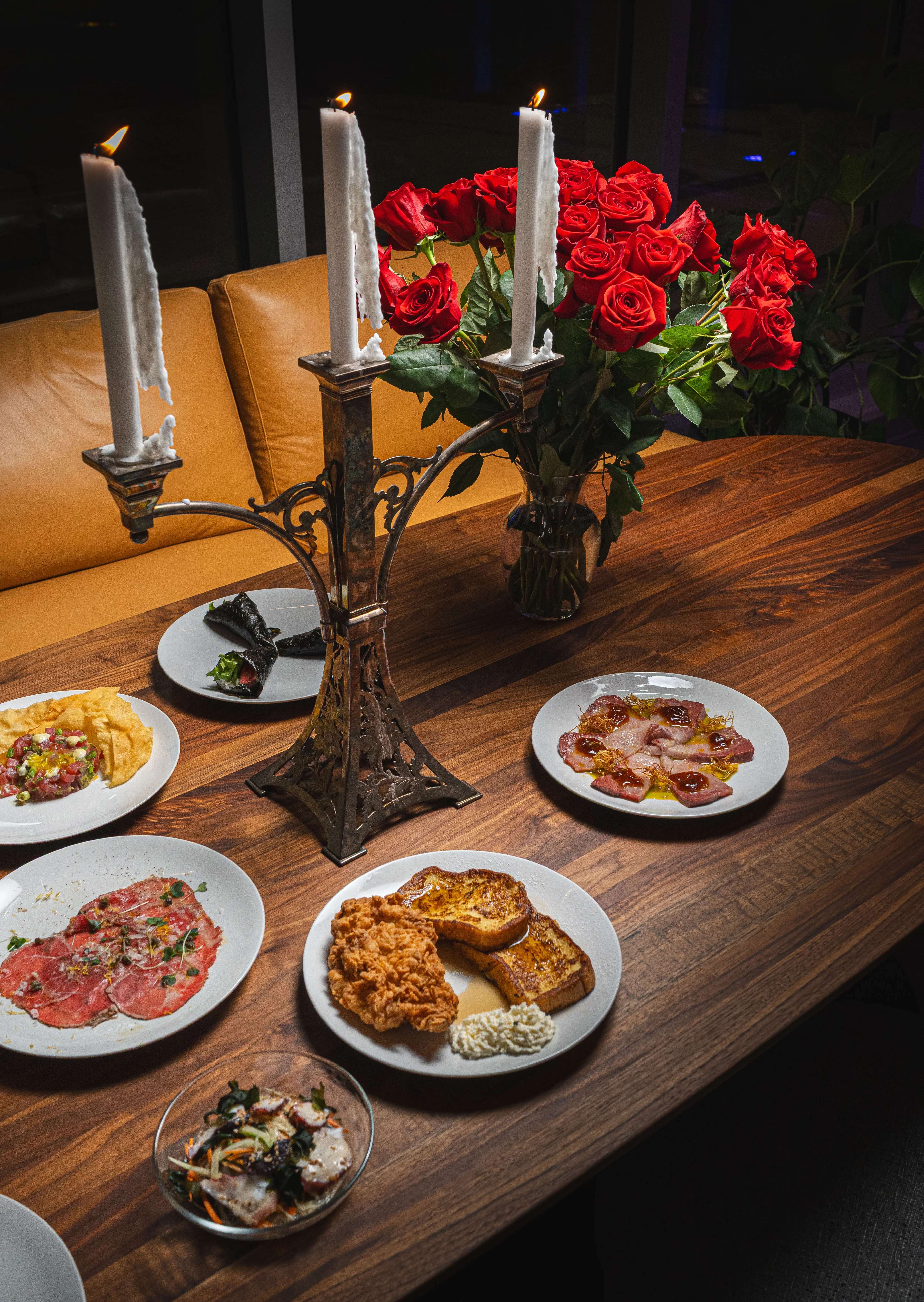 Elegant dining setup with assorted gourmet dishes and red roses