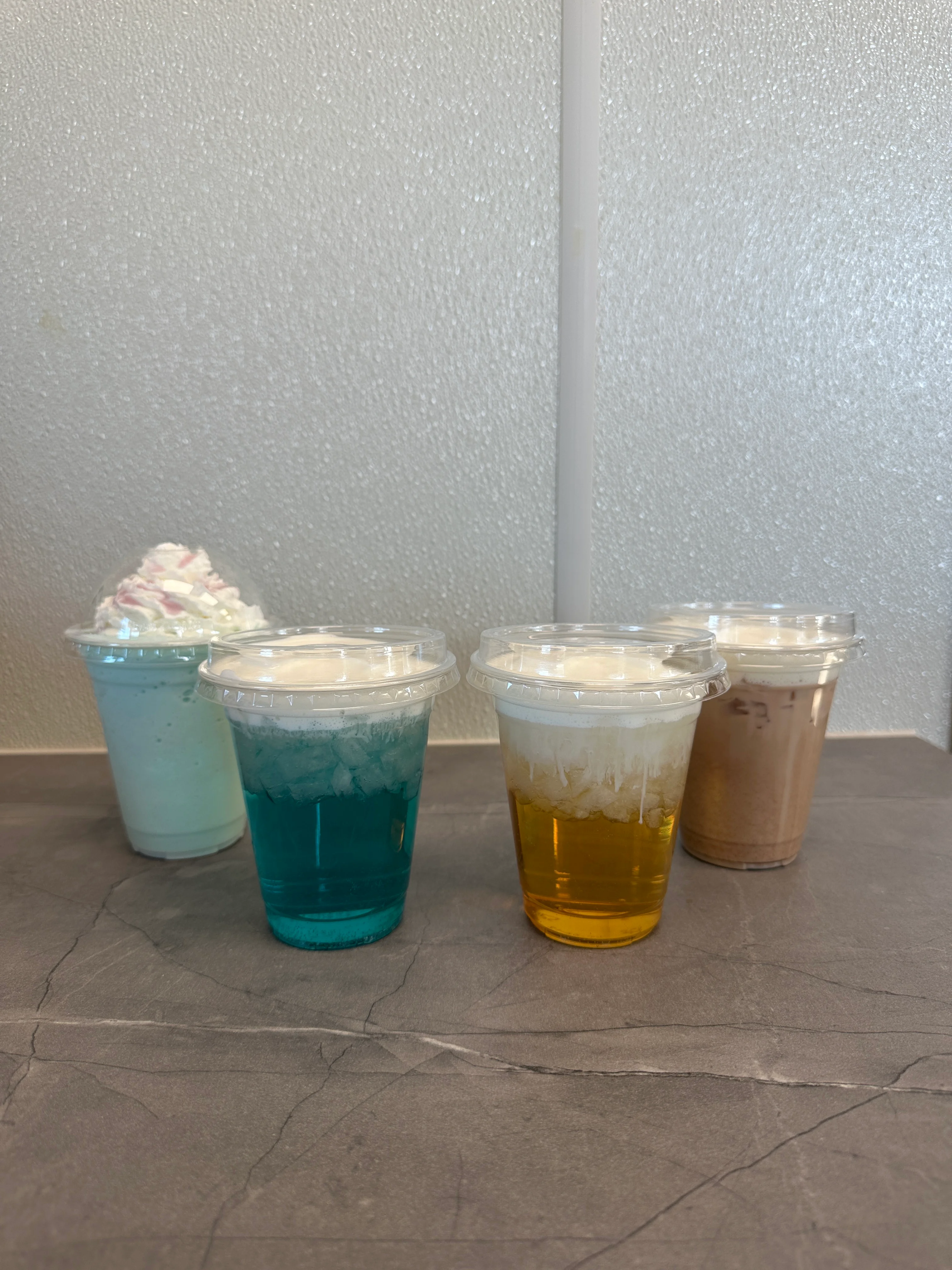 Colorful drinks with whipped cream in clear cups