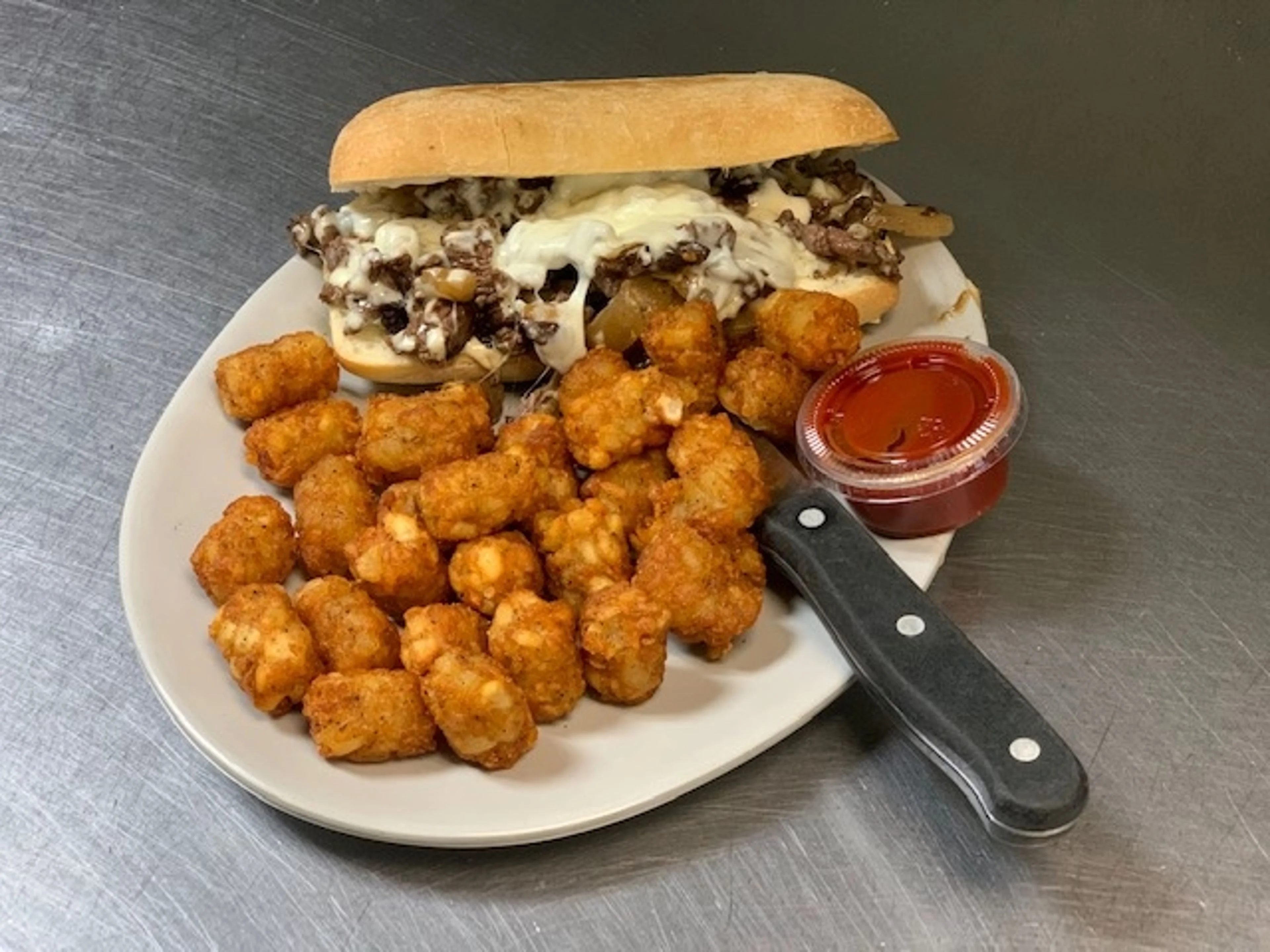 A Philly Cheesesteak with a side of tator tots