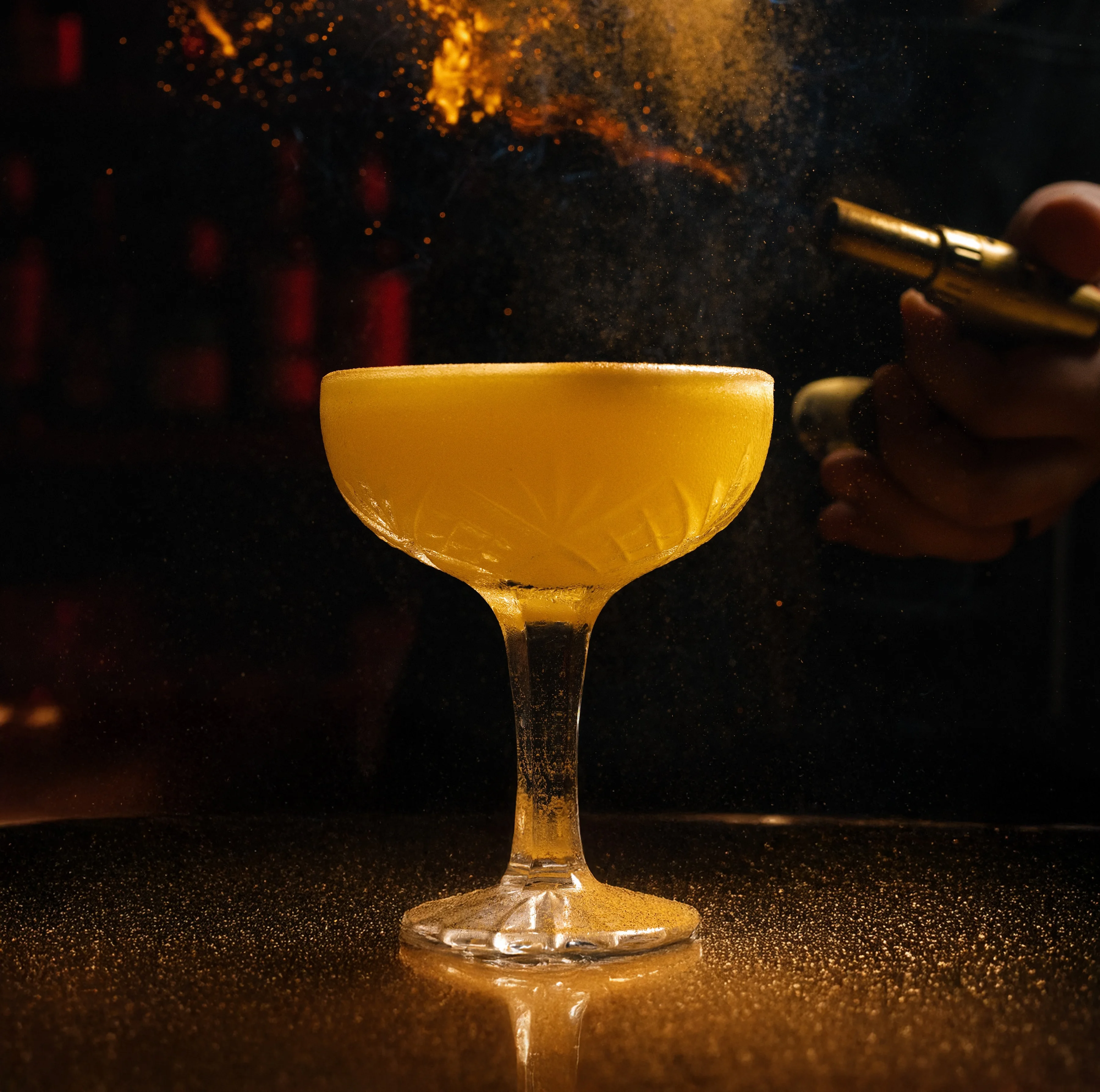Bartender igniting a cocktail with a dried orange slice