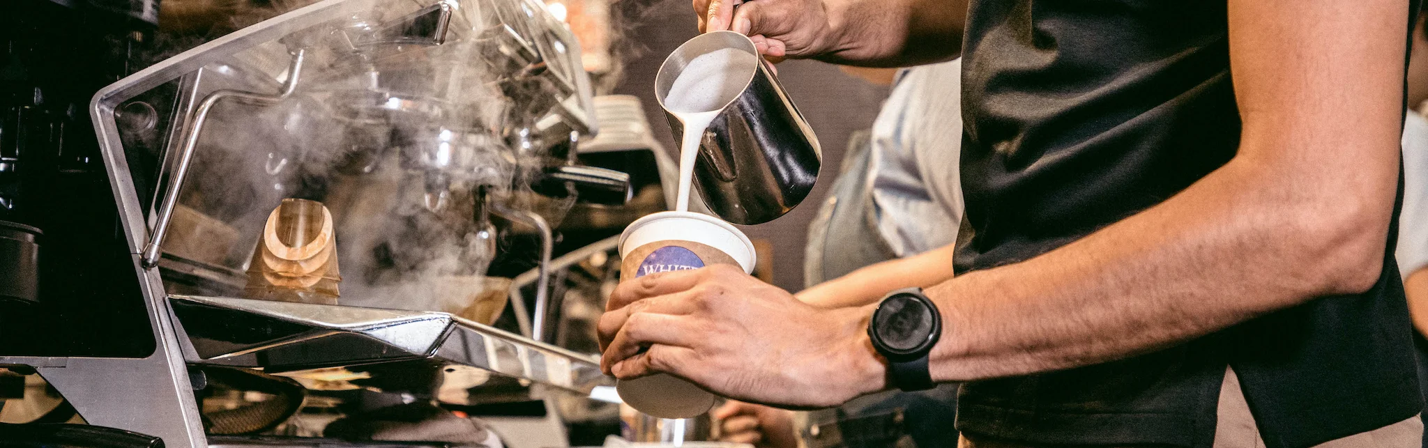 Barista pouring latte art into a coffee cup