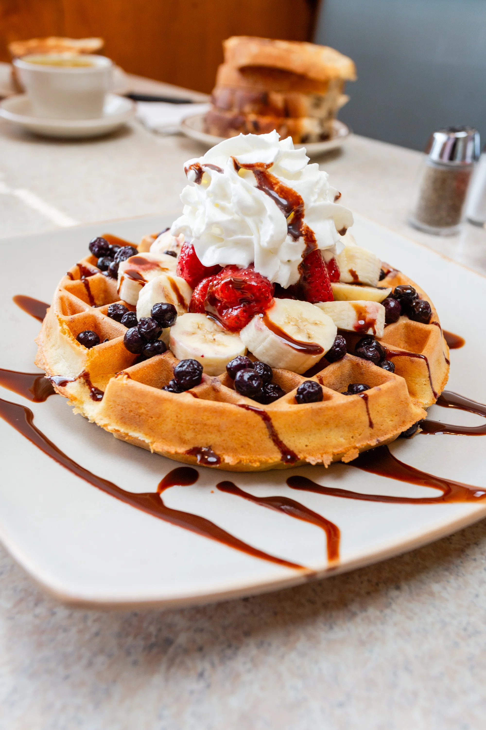 Belgian waffle topped with fruits and whipped cream
