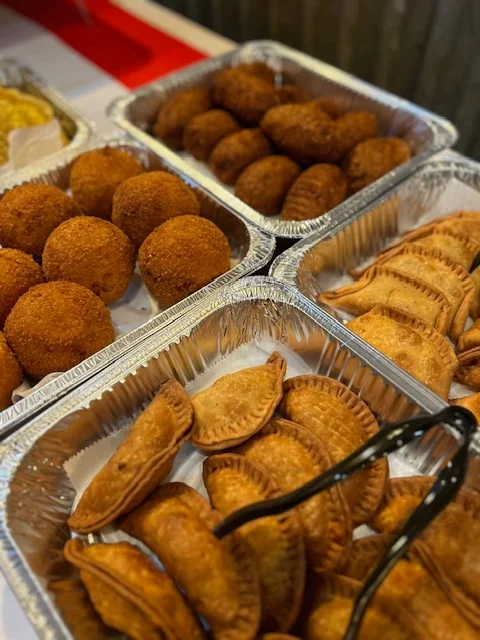 A serving of fried yuca sticks arranged in a tray, served with two small dipping sauces.