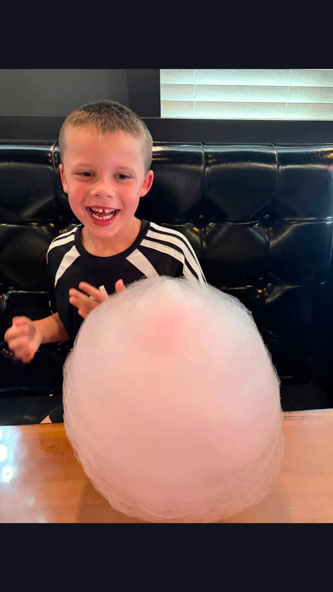 Child joyfully enjoying oversized pink cotton candy at a restaurant